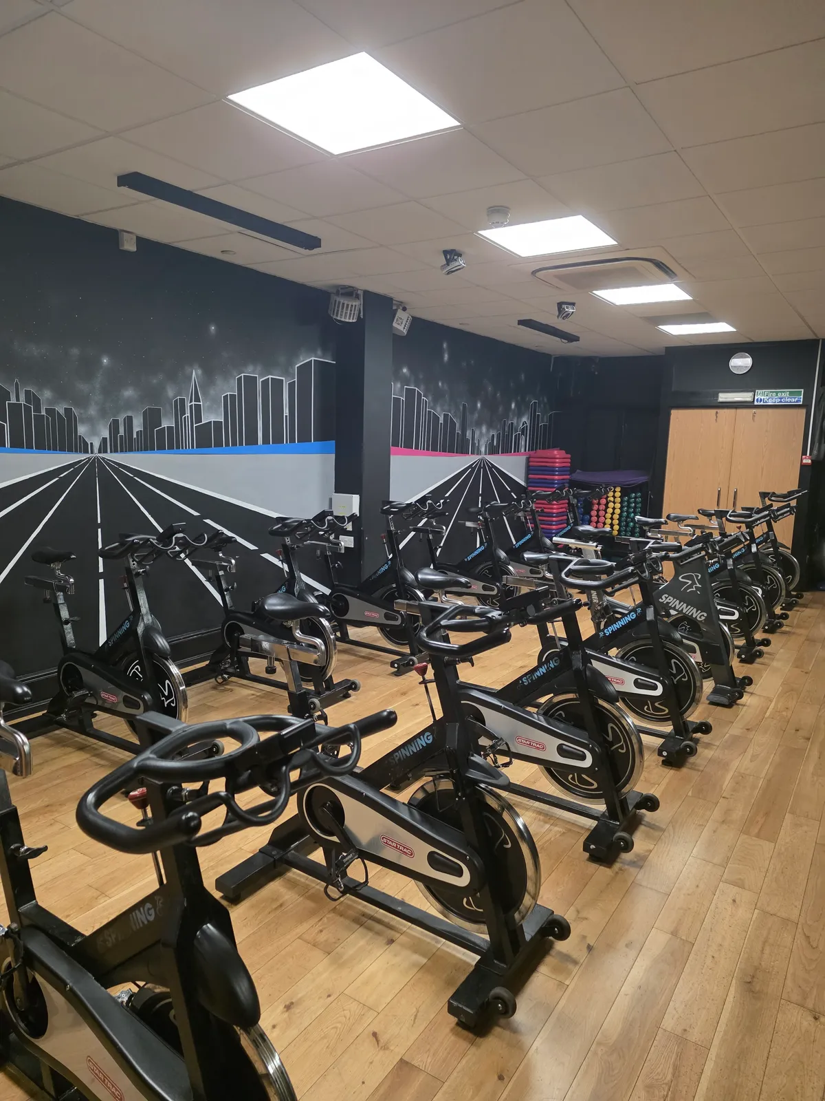 The spin room at Studio 20, with rows of Star Trac spin bikes facing a painted city-skyline mural